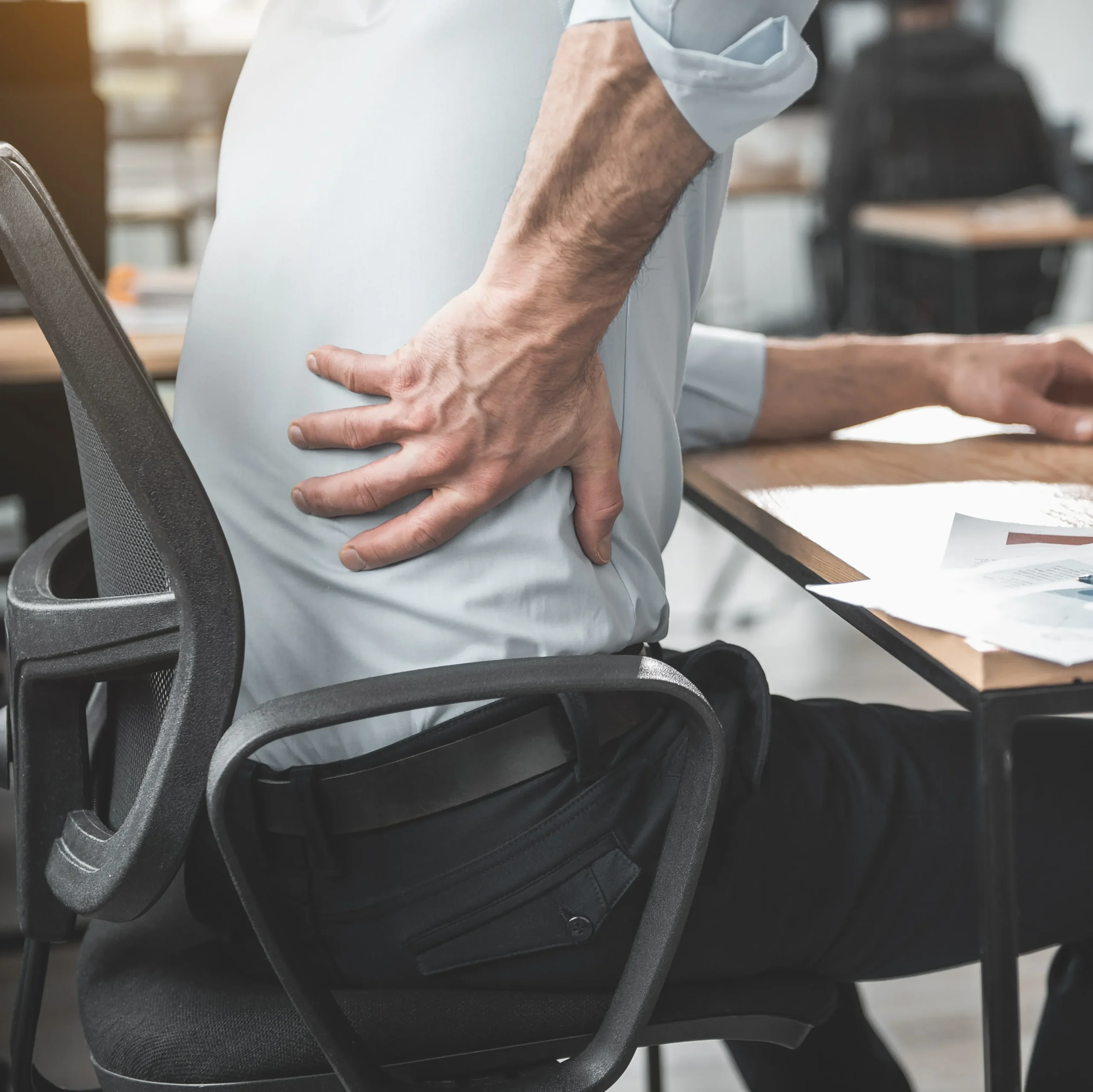 Man at desk holding lower back